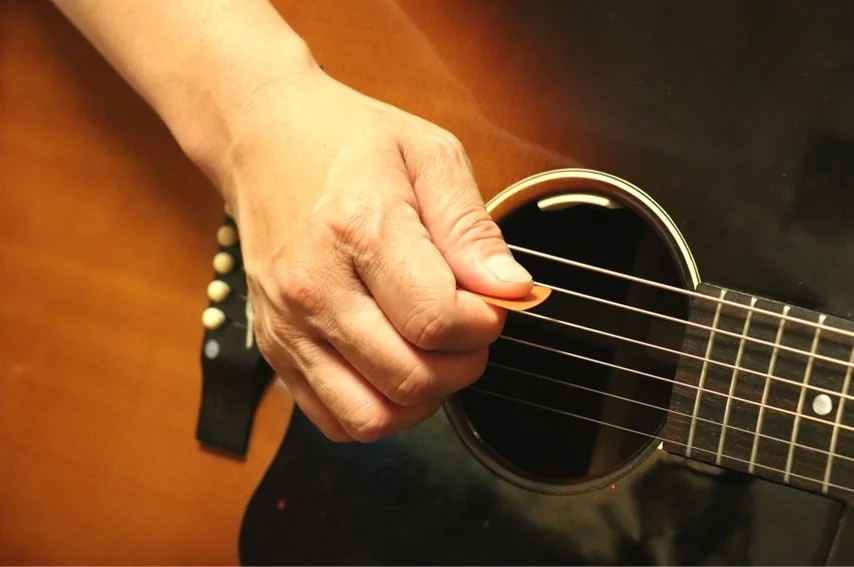 アコースティックギターを弾いてる右手。中指、薬指を閉じたクローズスタイル