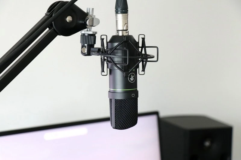 モニター前のデスク環境で、マイクアームとショックマウントに固定されたMackie EM-91Cコンデンサーマイクを撮影した商品イメージ